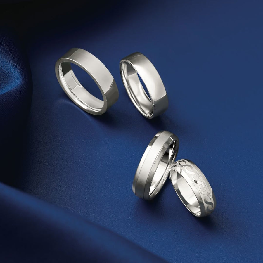 Platinum and white gold men’s bands on navy fabric