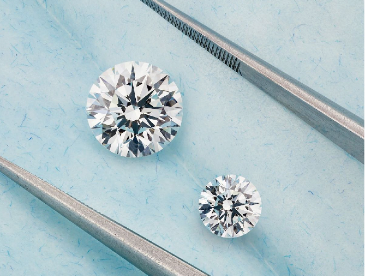 Two round diamonds compared side by side with tweezers
