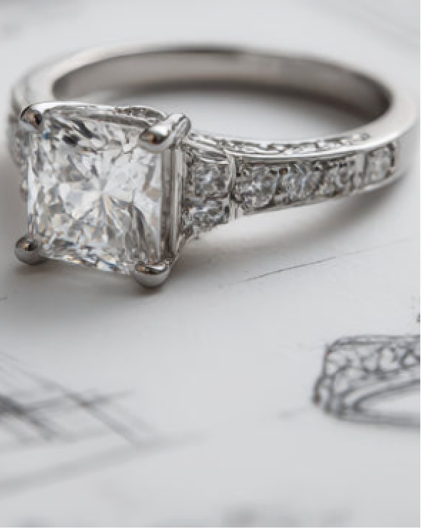 A diamond ring resting on a hand-drawn design sketch