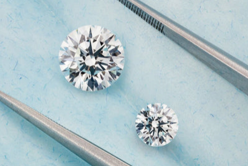 Two loose round diamonds being compared with tweezers