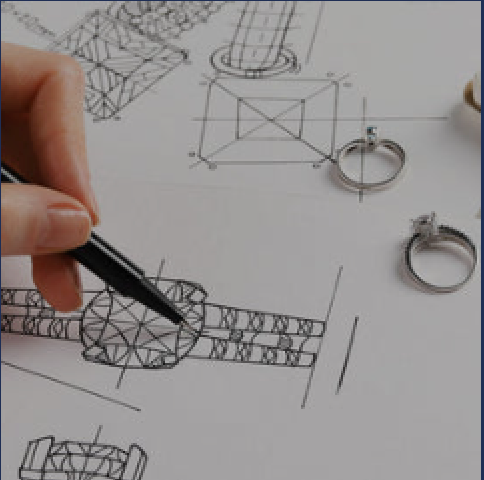 A designer sketching ring options beside two finished rings on the studio table