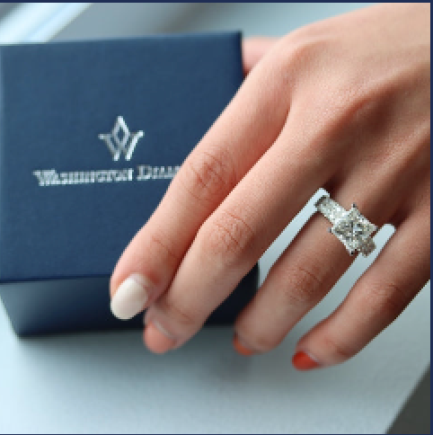 A finished engagement ring worn, with the navy Washington Diamond box alongside