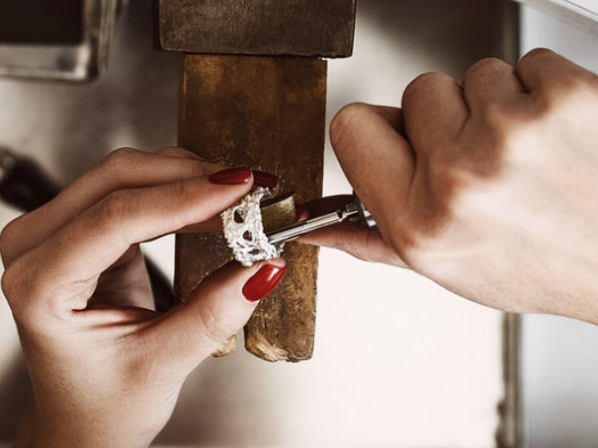 A jeweler working on a diamond ring at the bench in the on-site repair shop